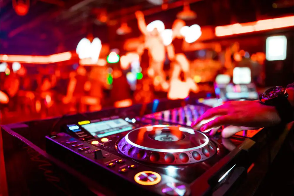 Dj mixing outdoor at beach party festival with crowd of people in background