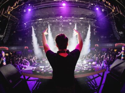 DJ in nightclub with hands up and cryo canons
